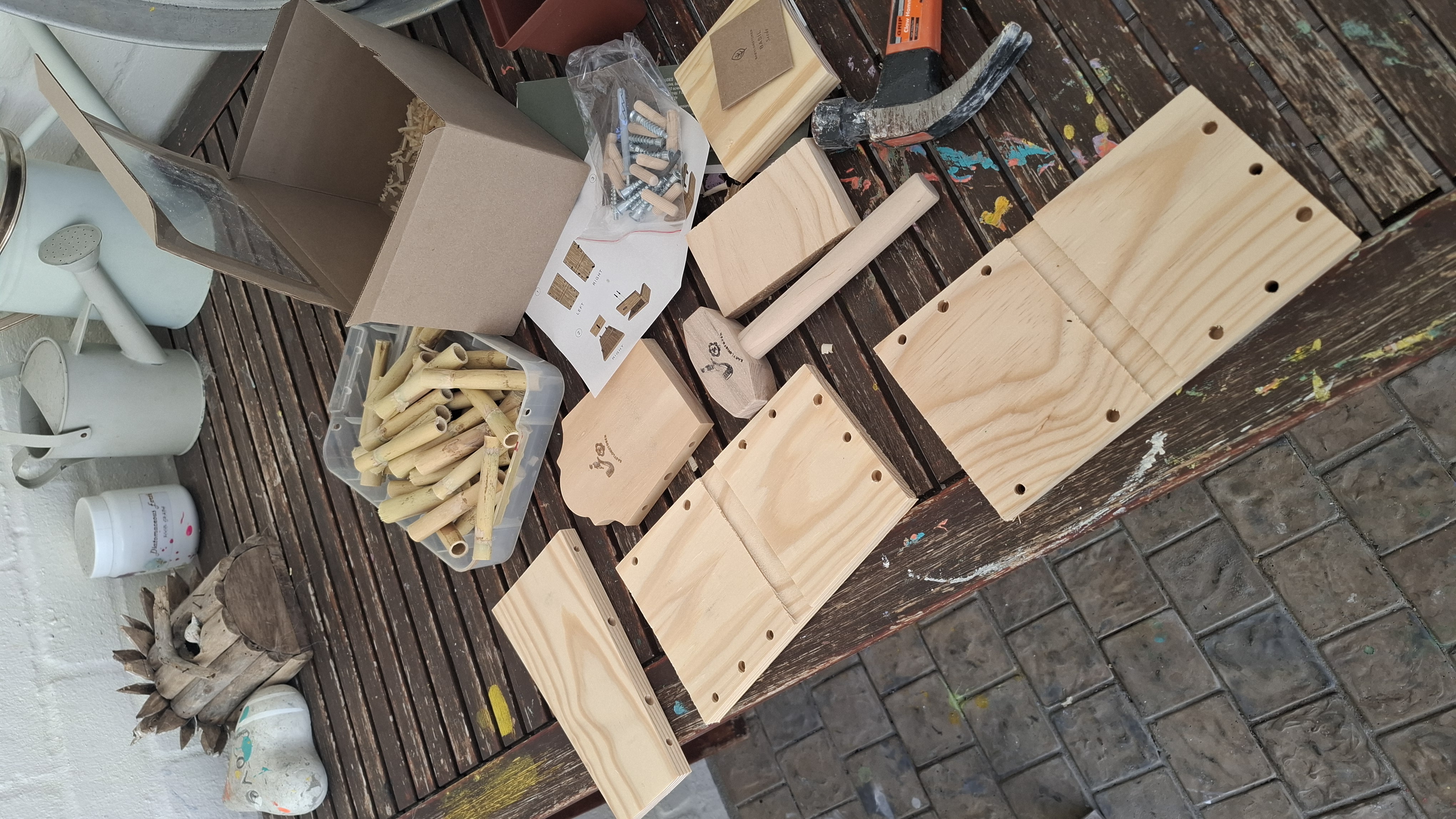 The Bug House kit laid out before assembly: pre-cut wooden panels, bamboo tubes, bolts, and instructions